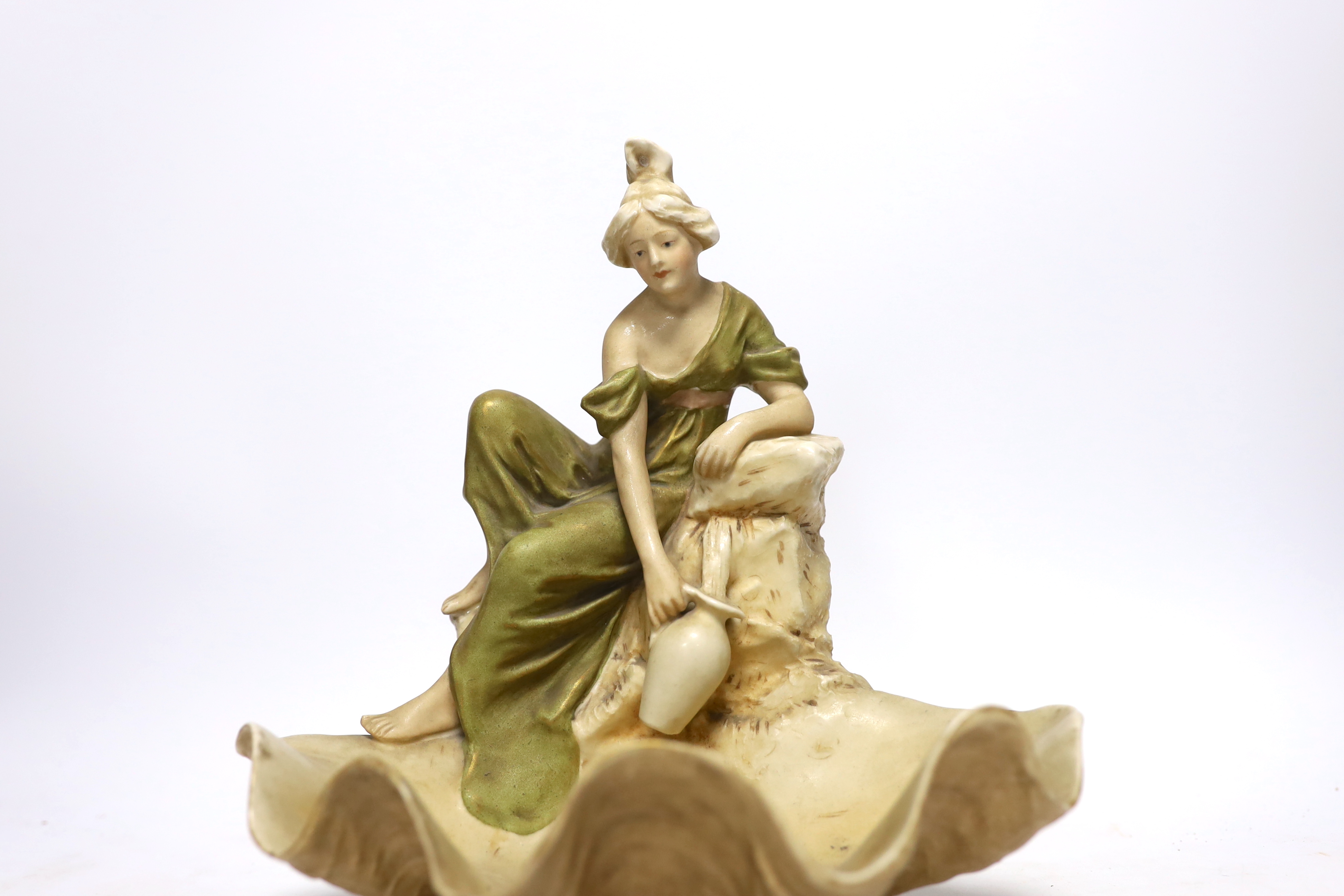 A Royal Dux figure of a water carrier by a shell shaped pool, 26cm high